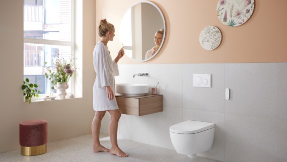 Kobieta w łazience z Geberit AquaClean Alba - ekonomiczną toaletą z funkcją bidetu i natrysku Kobieta w łazience z Geberit AquaClean Alba - ekonomiczną toaletą z funkcją bidetu i natrysku