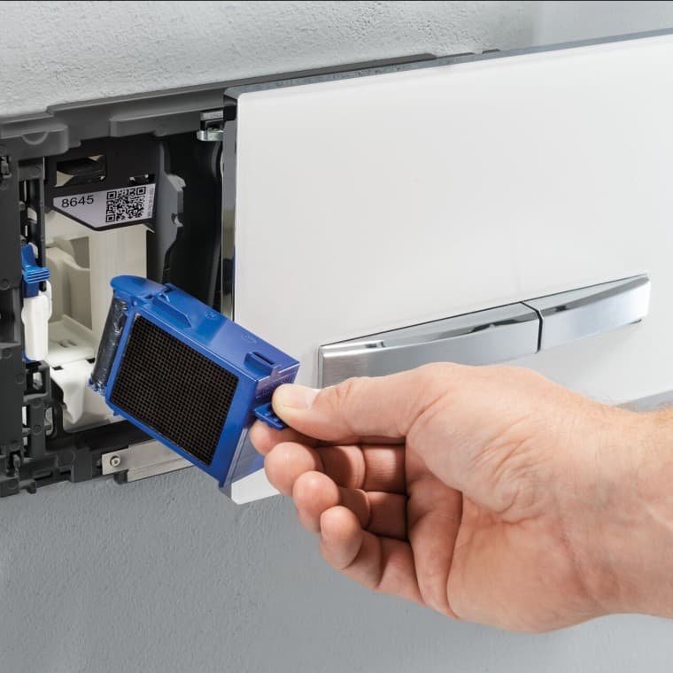 Dłoń umieszcza filtr oraz wkład do modułu do usuwania nieprzyjemnych zapachów w przycisku spłukującym Dłoń umieszcza filtr oraz wkład do modułu do usuwania nieprzyjemnych zapachów w przycisku spłukującym